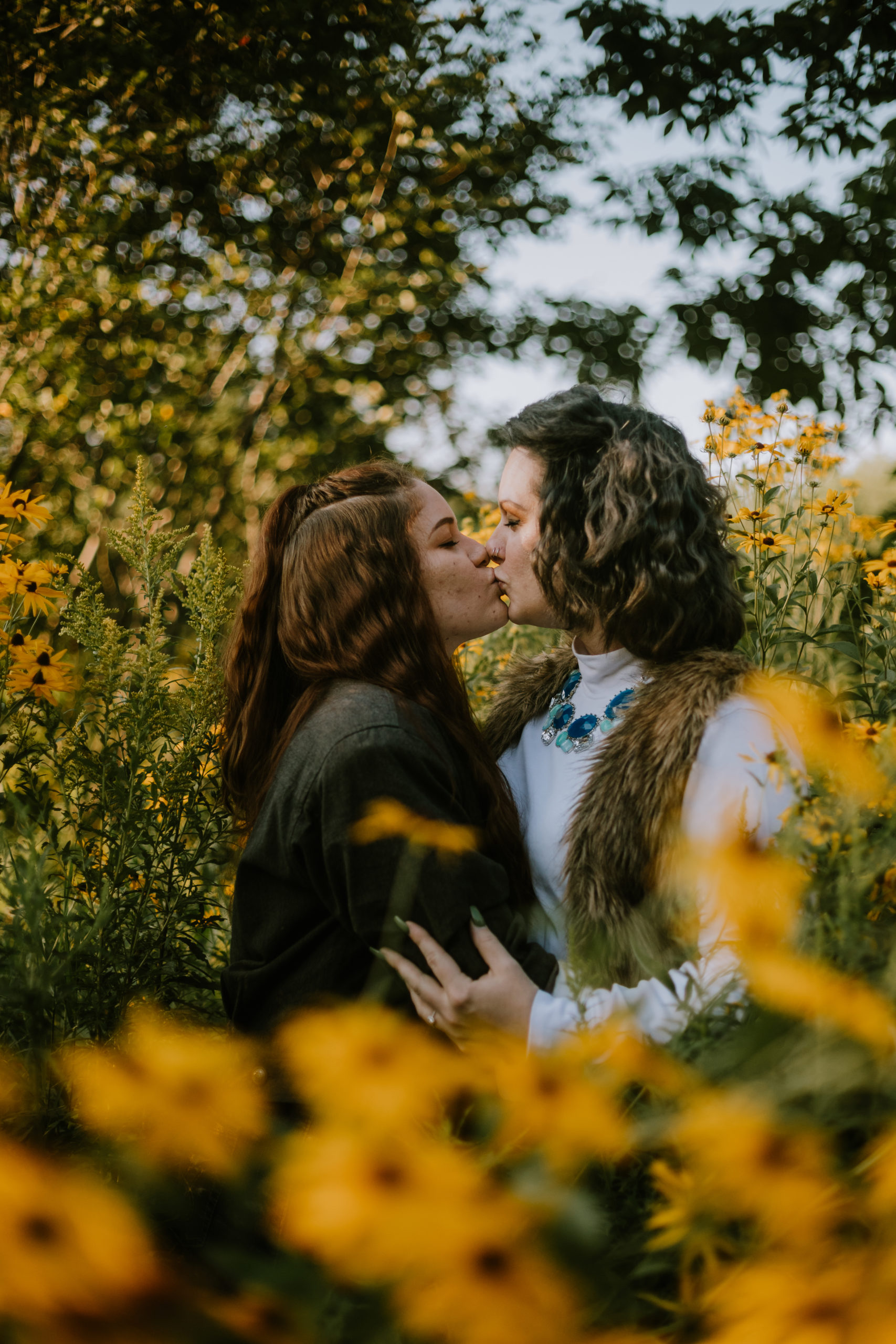Two women kissing in a field of black eyed susans.