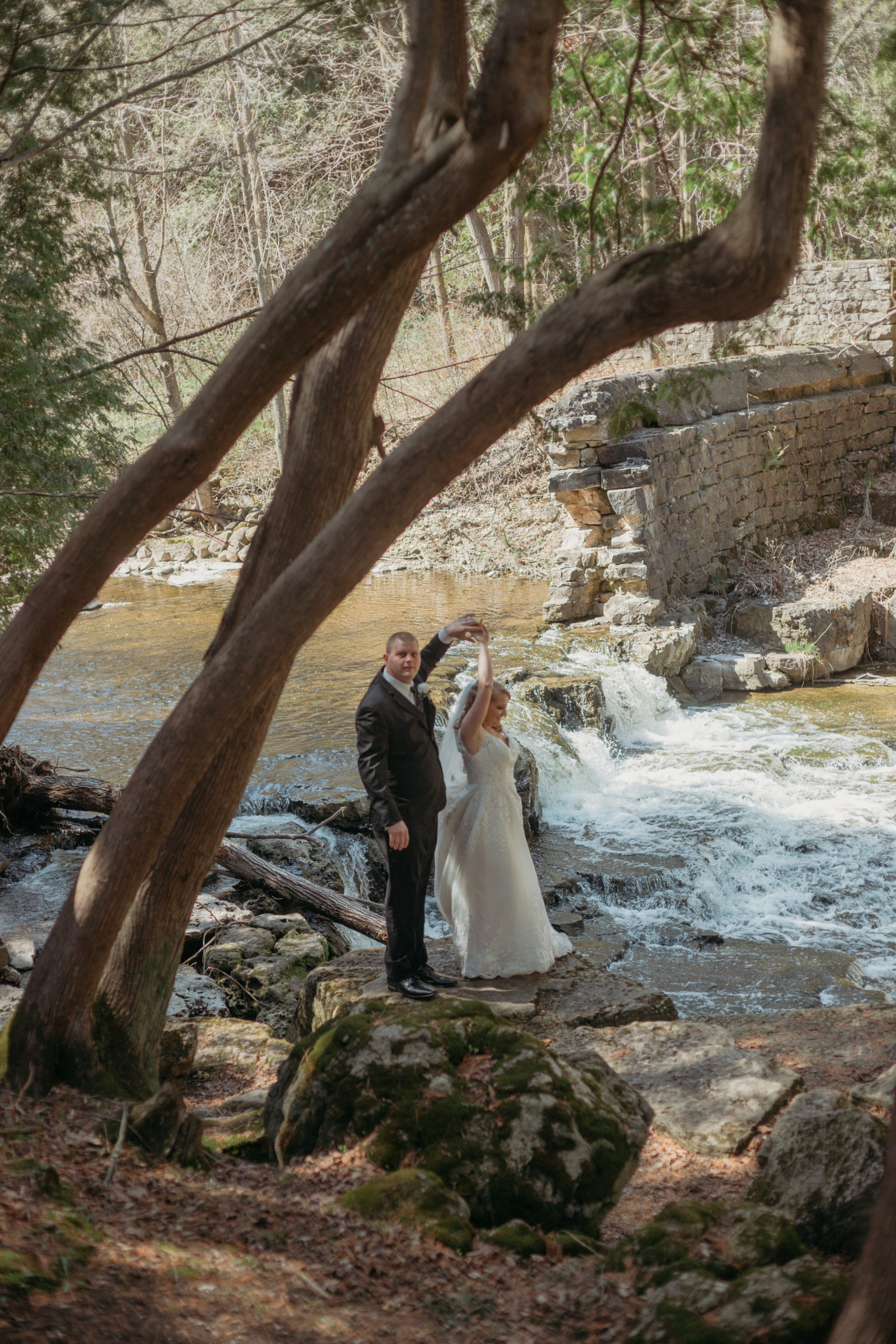 Bride and groom dancing in front of a waterfall