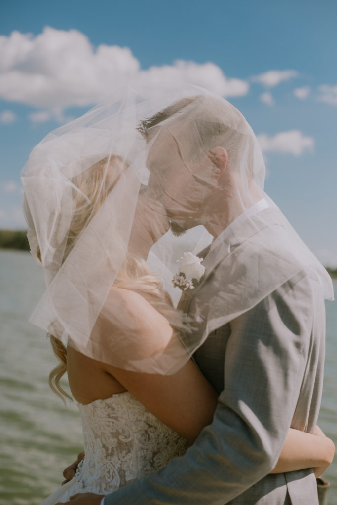 Bride and groom kissing under her veil during their summer wedding day in Green Bay, WI.