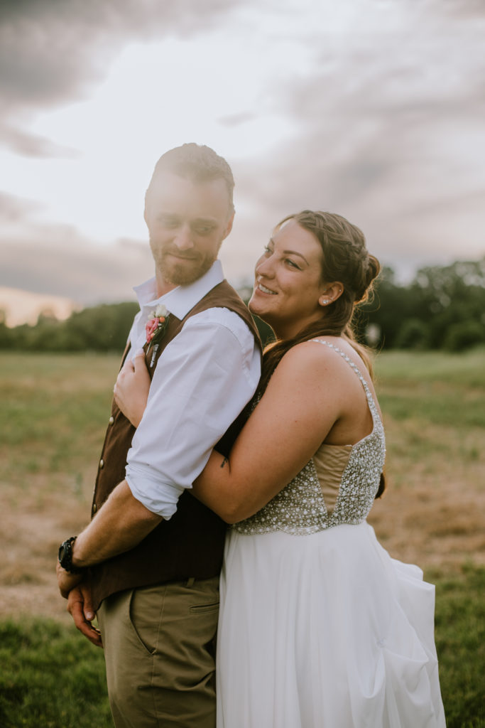 Bride and groom looking dreamy and in love at sunset during their traditional barn wedding.