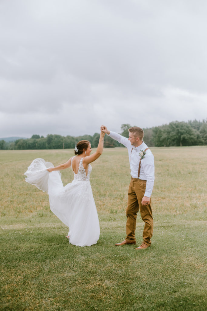 Bride and groom twirling in a field during their summer backyard wedding day.