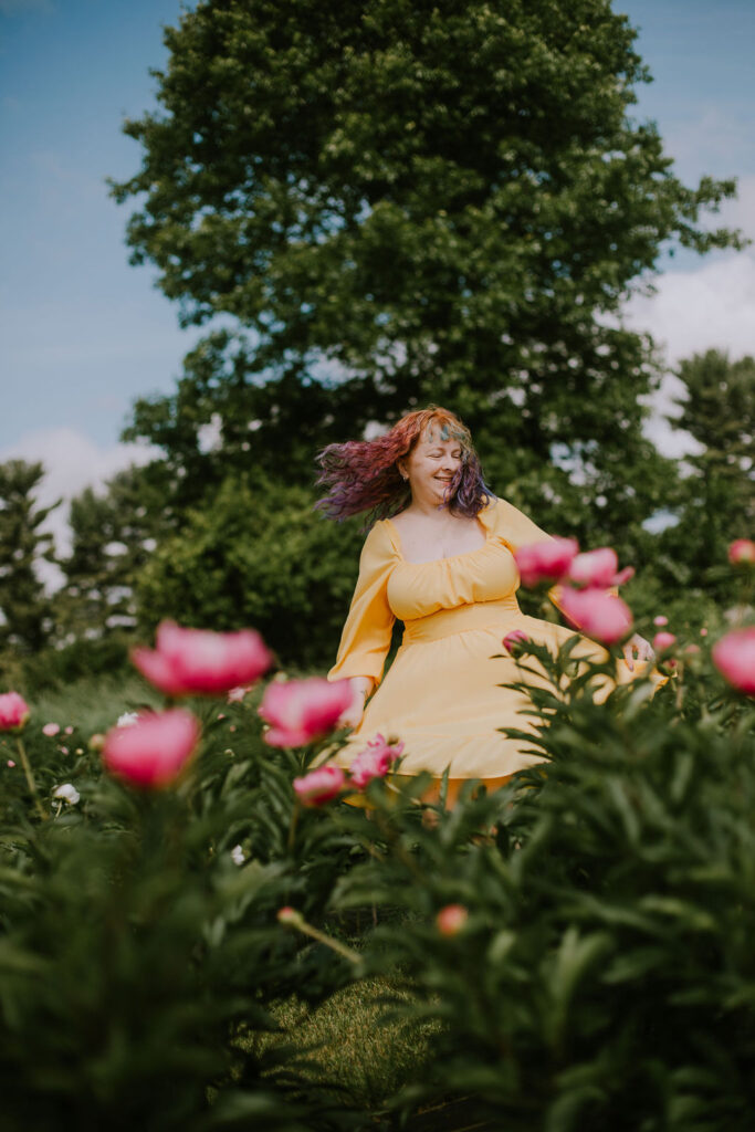 Girl in a yellow dress spins in a peony field during Peony Days at Kuckuk Farms.