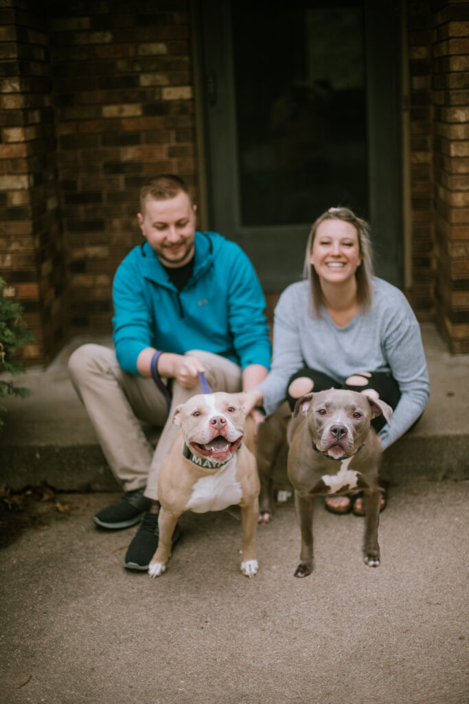 Couple sitting on their front porch with their two pit bulls during their at-home anniversary session