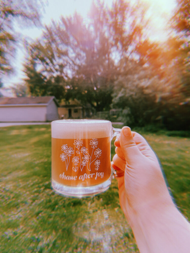 Glass coffee mug illustrated with daisies and text that reads chase after joy for my monthly Currently post