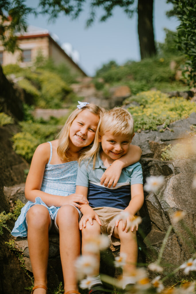 Brother and sister hugging on stone steps during their garden family session.