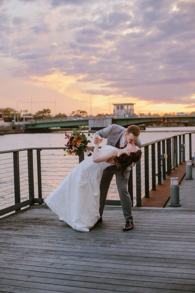 Bride and groom kissing on the river walk at sunset during their downtown Manitowoc wedding day.