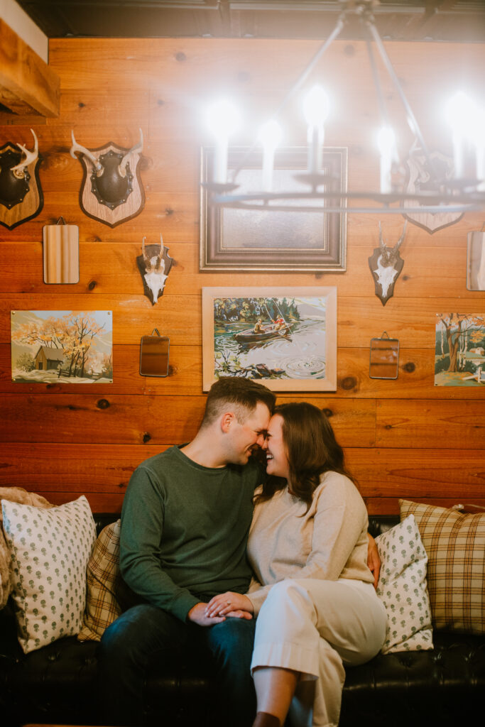 Couple snuggles on the couch in the lodge during the Camp Elsewhere engagement session in Waupaca, WI.