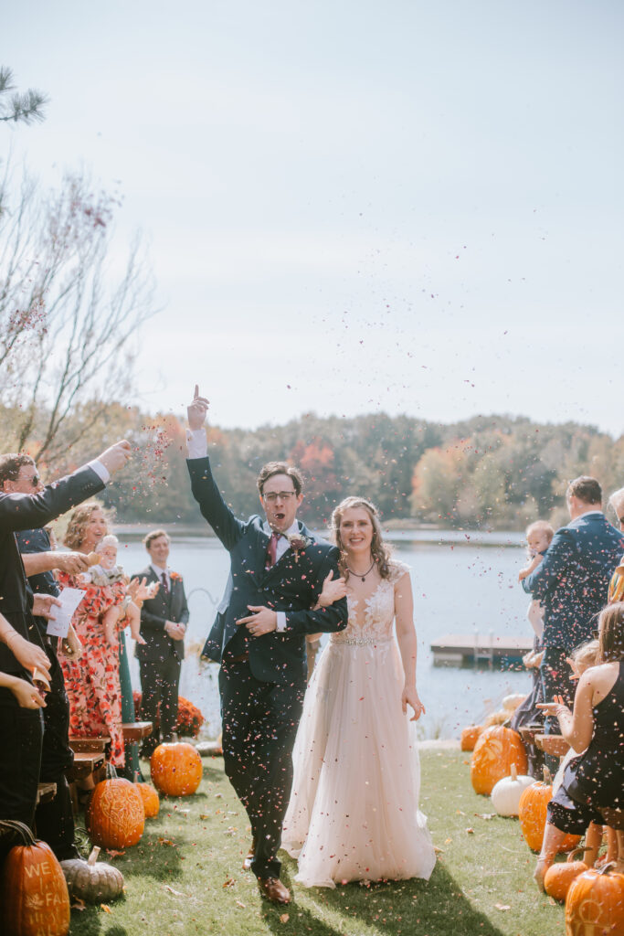 Bride and groom walk back up the aisle while their guests throw flower petal confetti during their romantic Danes Hall wedding day.