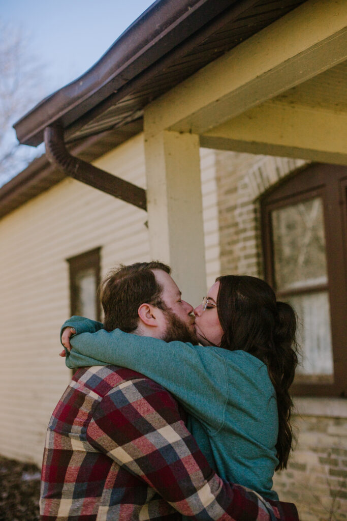 Couple kissing behind the High Cliff General Store during their engagement session at High Cliff State Park
