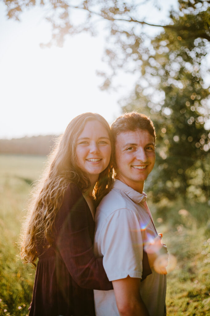 Couple smiling and holding each other during their golden hour engagement session on the Ice Age Trail in Waupaca, WI.