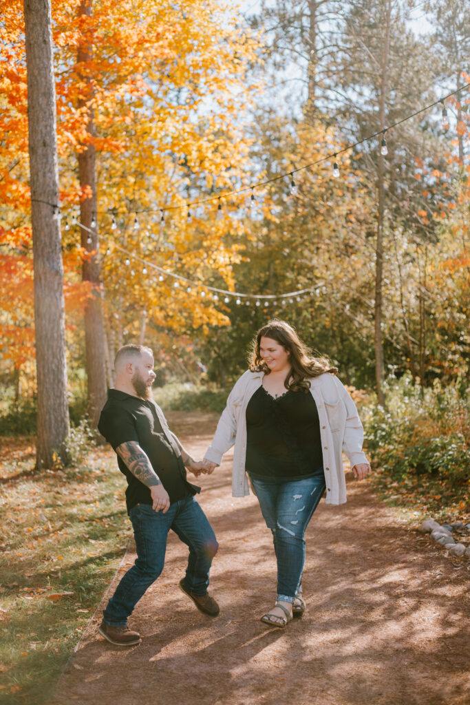 Couple playfully dancing during their morning Monk Botanical Garden engagement session in Wausau, WI.